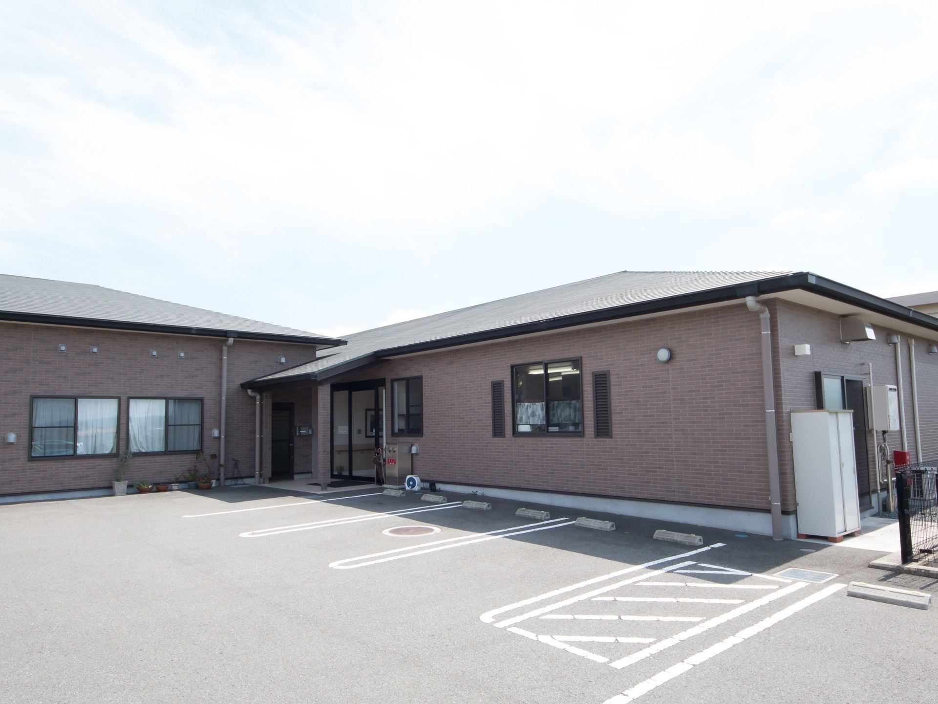 施設は平屋建てで、レンガ調の外壁である。敷地内には数台が停められる車の駐車スペースが用意されている。