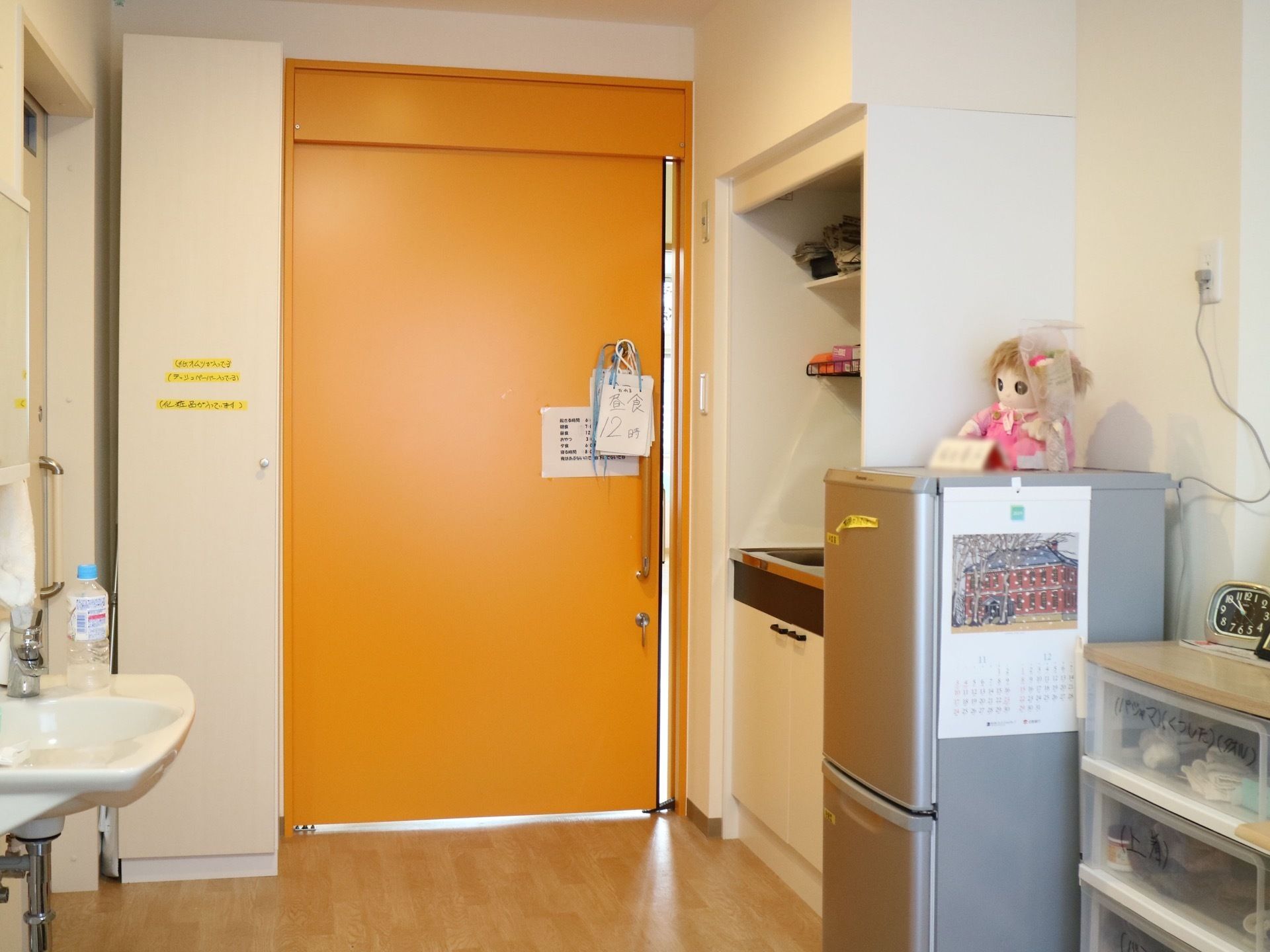 ミニキッチン、洗面台、冷蔵庫、衣装ケースが備えられた居室である。一人の時間を快適に過ごせる環境を整えている。