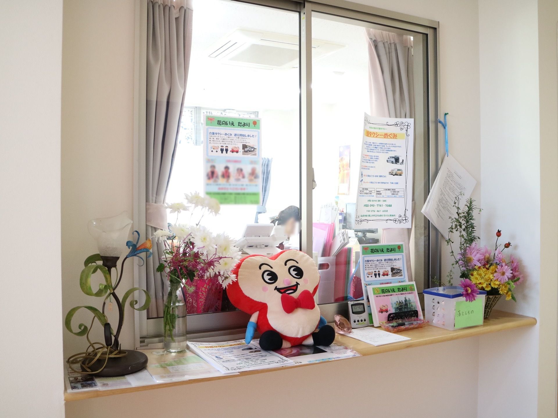 受付には小窓があり、その前にはカウンターが設けられている。カウンターの上にはチラシや花、ランプなどが置かれている。