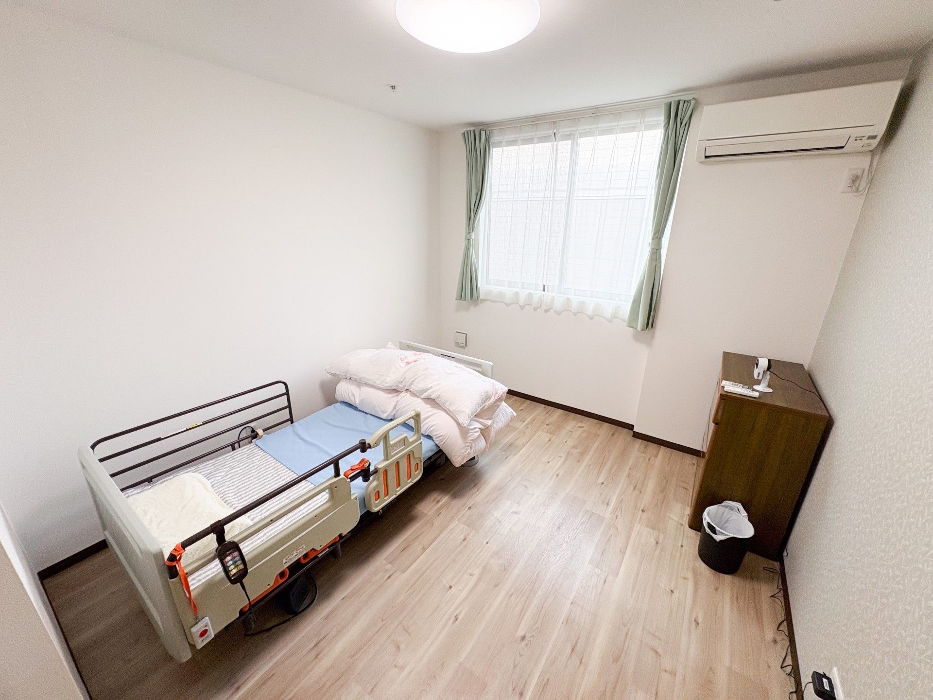 大きな窓が付いた居室はフローリング。左手にはキッチンがあり、右手にはエアコンがある。