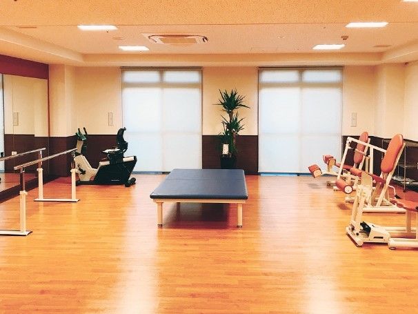エプロン姿のスタッフがベッドに横になっている高齢者の女性に話しかける。二人とも笑顔。