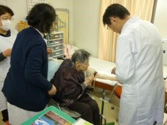 施設内の医務室で医師の診察を受ける、スタッフに付き添われた入居者様