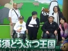 遠足に出かけた先の看板前で並んで写真に納まる入居者様