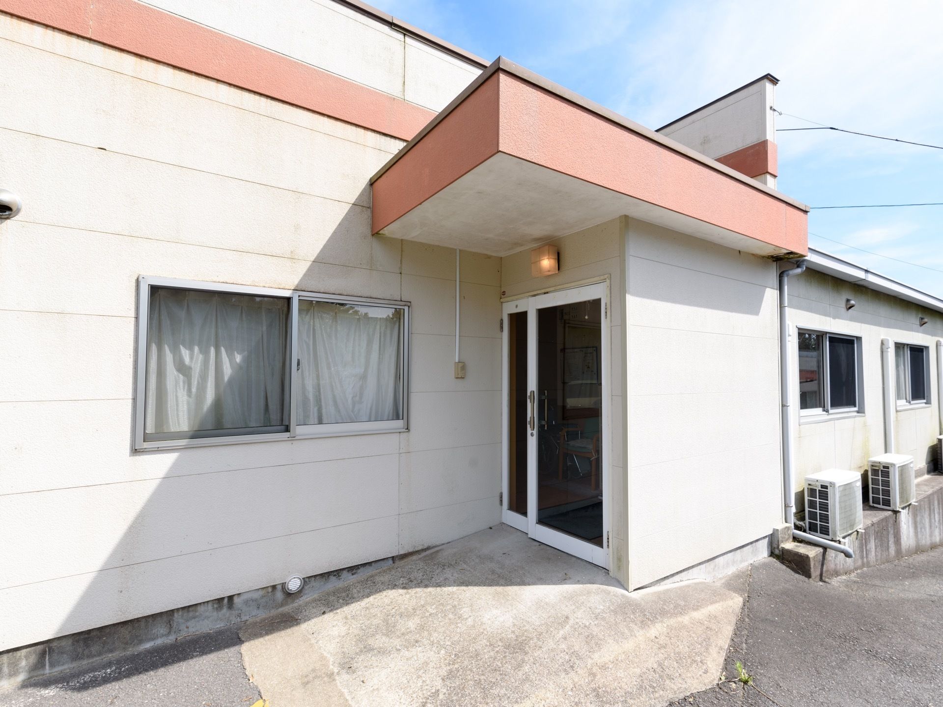 出入口の上部には壁つけの照明が設置されている。入居者様が夜間、出入りする際にも明るく照らされており安心である。