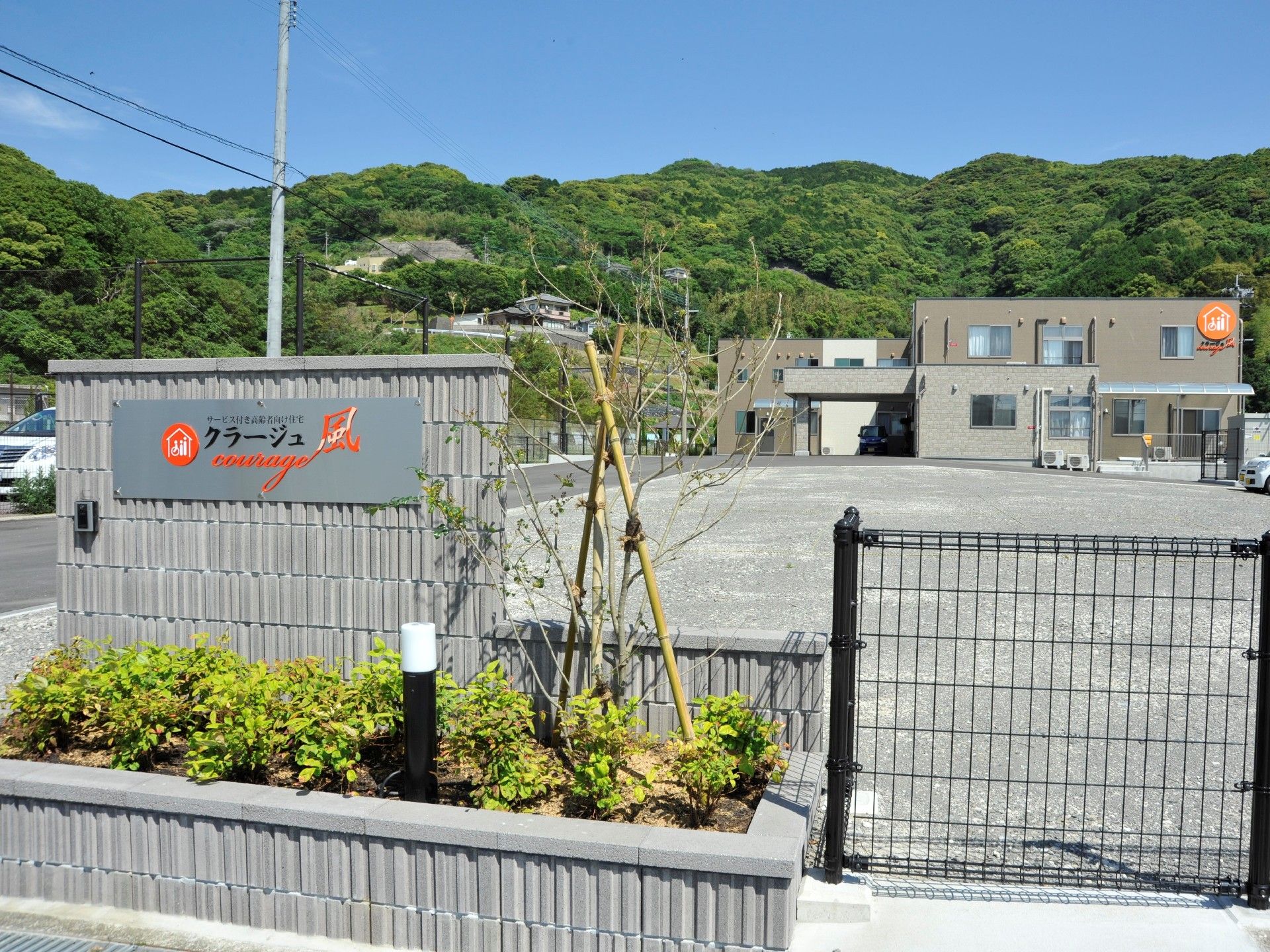 低木が植えられ、照明が設置されたスペースがある施設名が書かれた看板