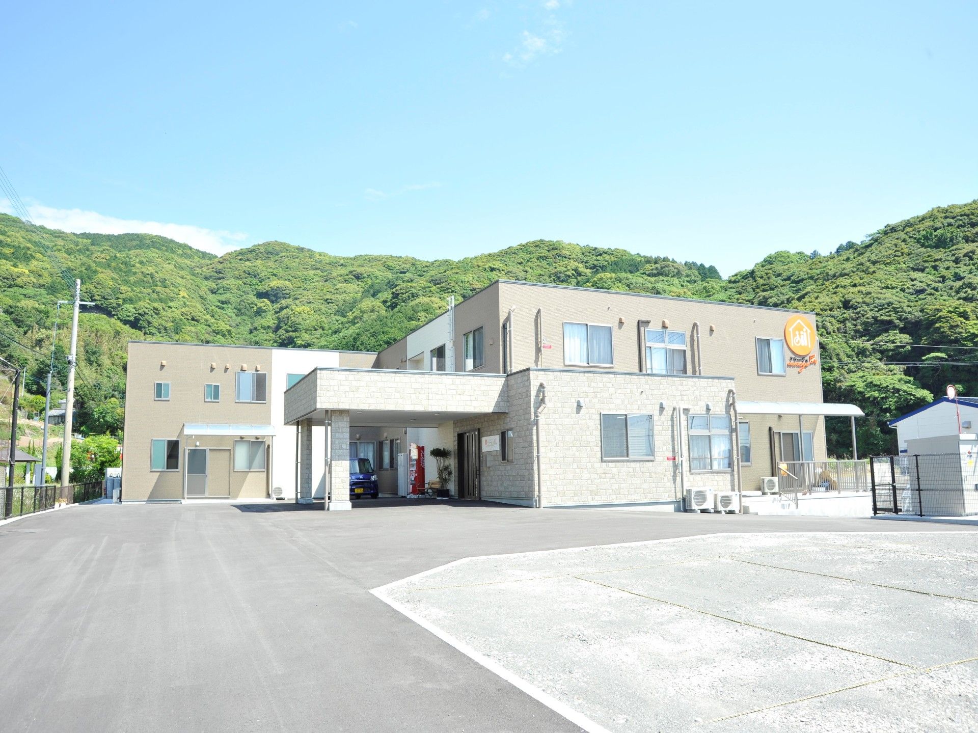 大きな森の前に建設されている、二階建てで横長な施設外観