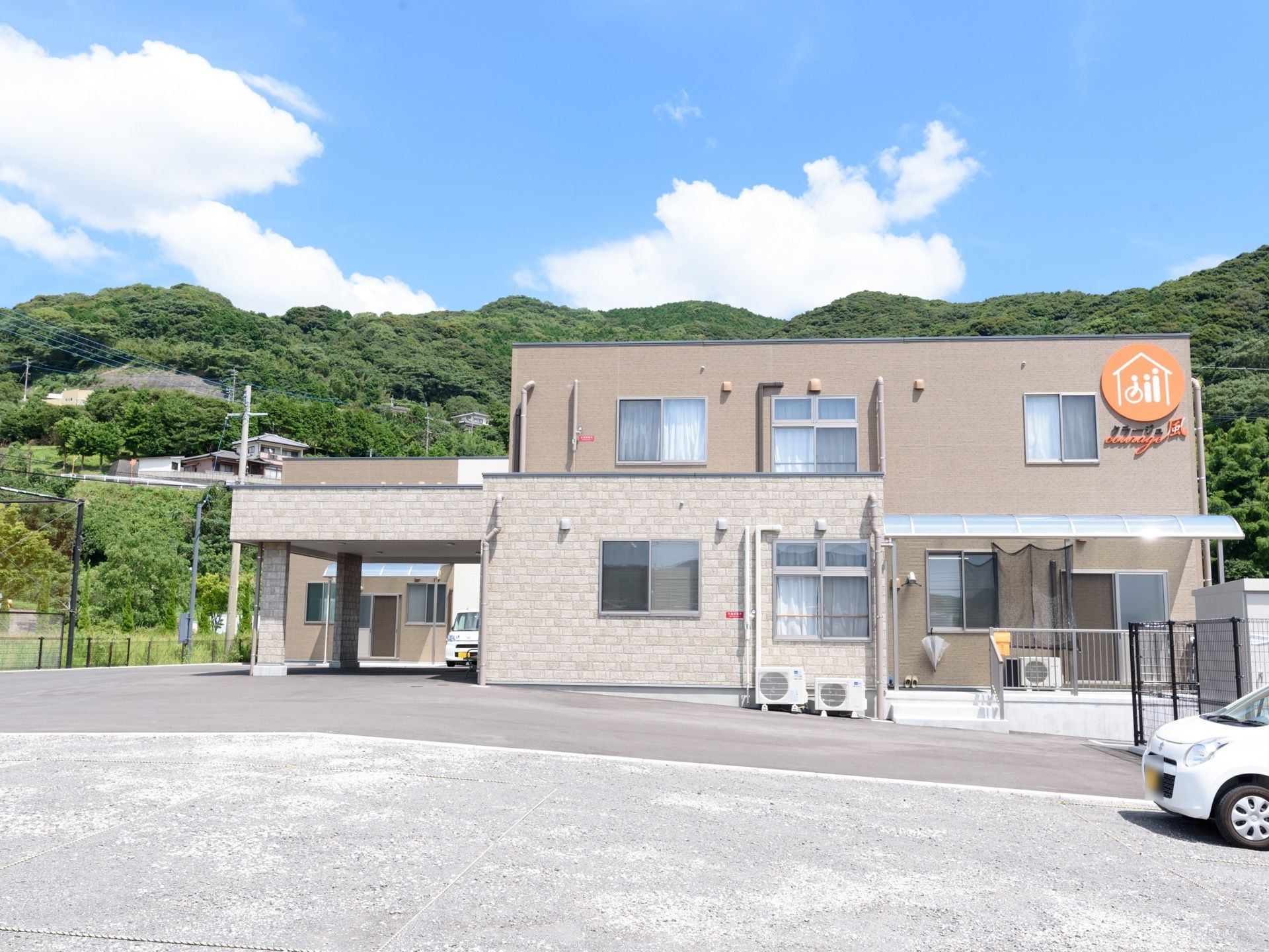 ベージュ色の外壁の２階建ての建物になっている。敷地は広く、大きな駐車場を完備しており車での来訪も便利である。