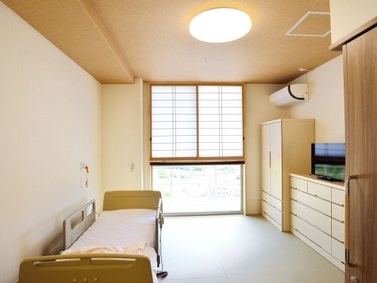 照明と収納、介護用ベッド、緊急コールが写っている施設内の部屋の様子。障子から外の明かりが漏れている様子が分かる