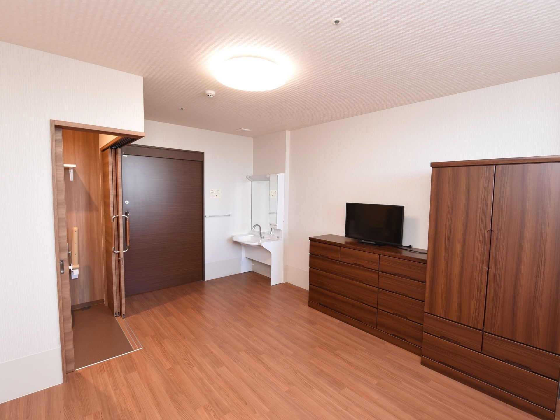 居室のドアのすぐ近くに、トイレと洗面化粧台が設置されている。壁の隅に、タンスが2種類用意されている。
