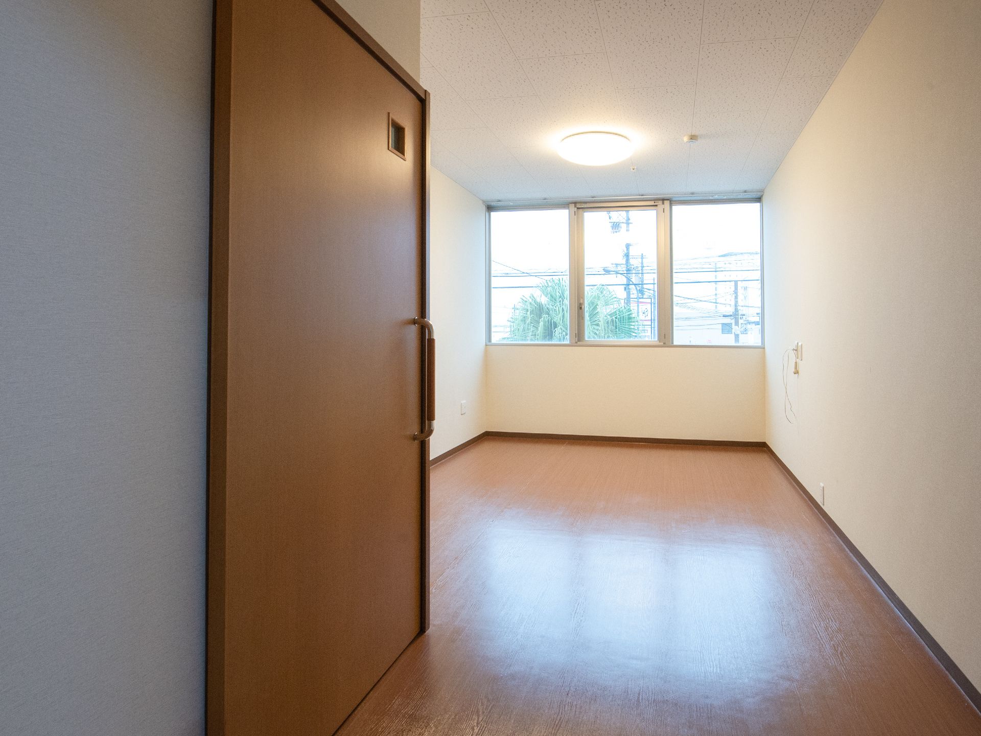 奥に窓があり、何も家具が設置されていない居室の風景