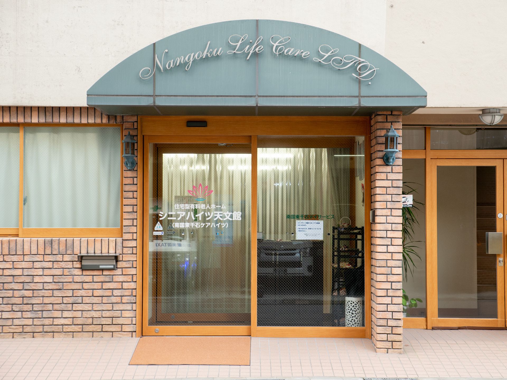 外壁がレンガ造りで洋風の照明が設置されている、おしゃれな施設入口