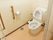 トイレの扉は開き戸を採用している。トイレットペーパーホルダ―の脇に縦方向の手すりがある。トイレ内は広々としている。