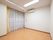 家具などが置かれていない居室内。壁には受話器のついたナースコールとエアコンが取りつけられている。大きな窓がある。