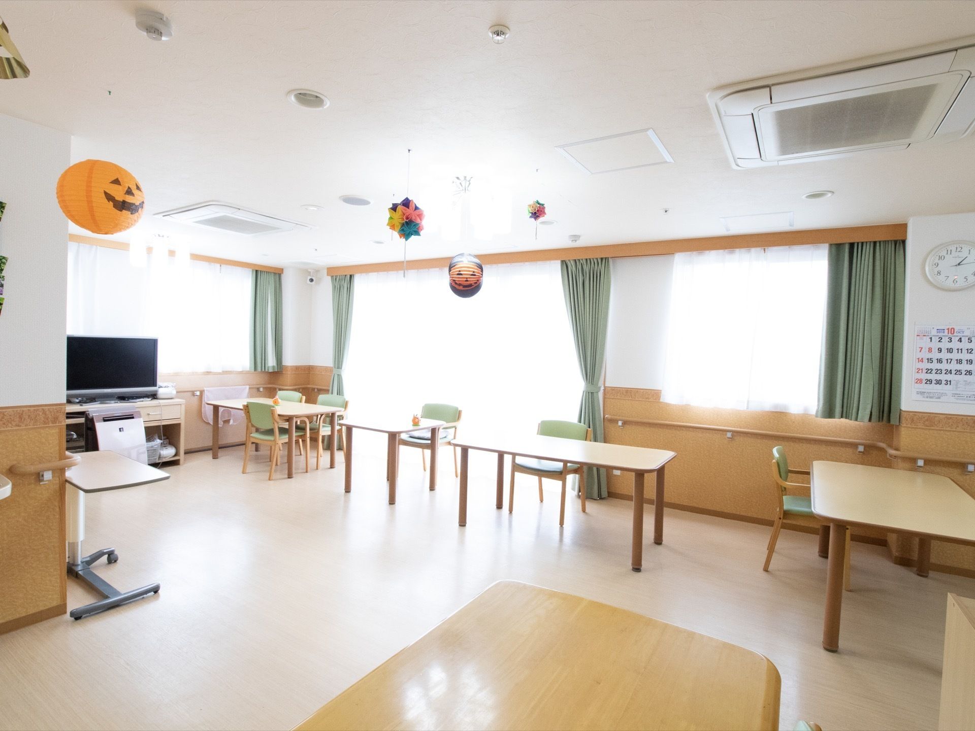 窓からよく日が差し込むリビングである。窓には落ち着いた色合いの緑色のカーテンが掛かっている。天井には、飾りが吊り下げられている。