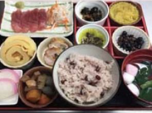赤飯とお刺身をメインとした豪華な食事。吸い物と8つの小鉢が添えられている。