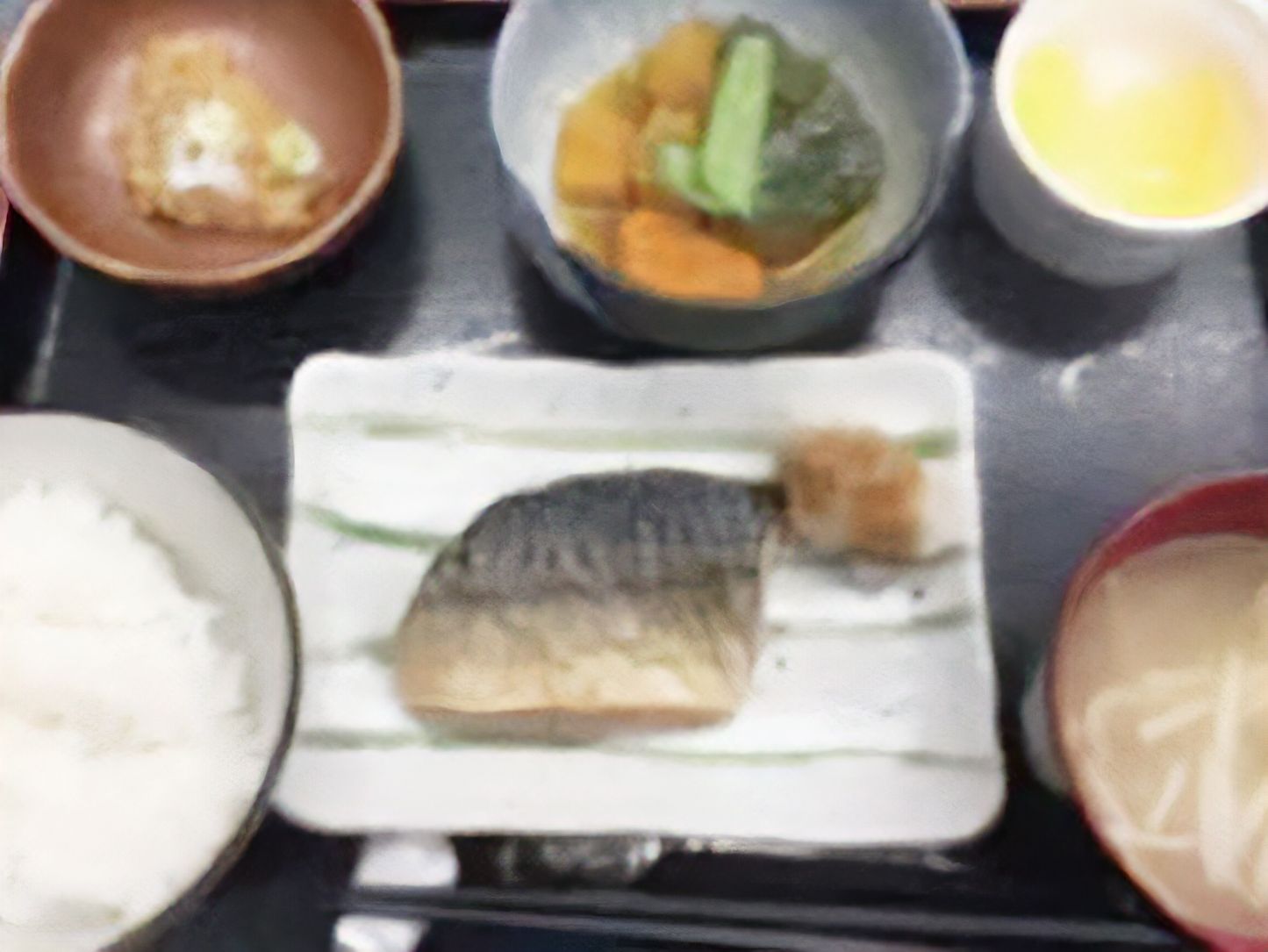 塩サバの乗った四角い和風の皿を中央に置き、その周辺を白ご飯・味噌汁・小鉢3品が囲んでいる。