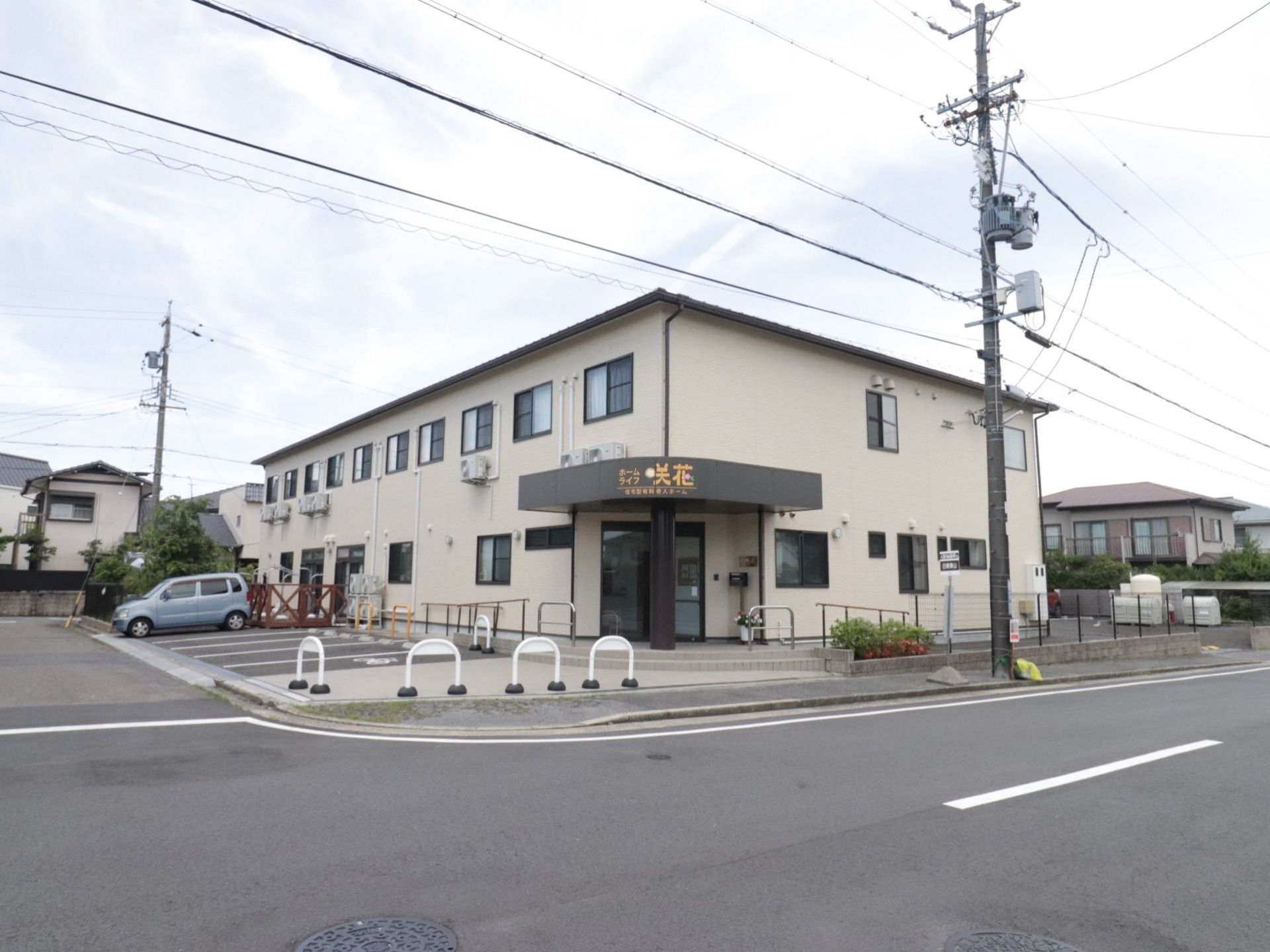 シンプルな作りの綺麗な外観。建物の目の前には駐車スペースが５台分ある。出入口には手すり付きのスロープが設置されている。