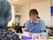 食事をしている入居者様と共にスタッフも座り、会話をしている。テーブルの上には、屑入れやボックスティッシュが置いてある。