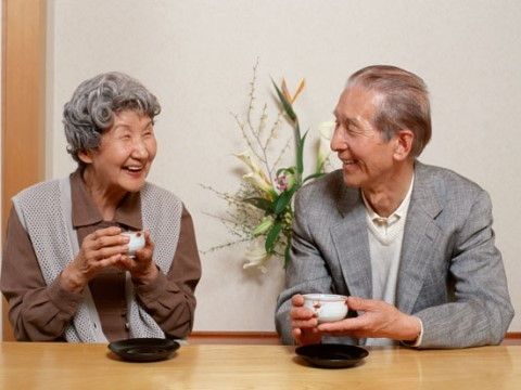 微笑みながら会話する老夫婦。お茶を飲んでくつろいでいる様子が分かる写真