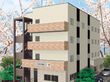 淡い色合いの建物が写っている。数階建ての住まいであることがうかがえる写真