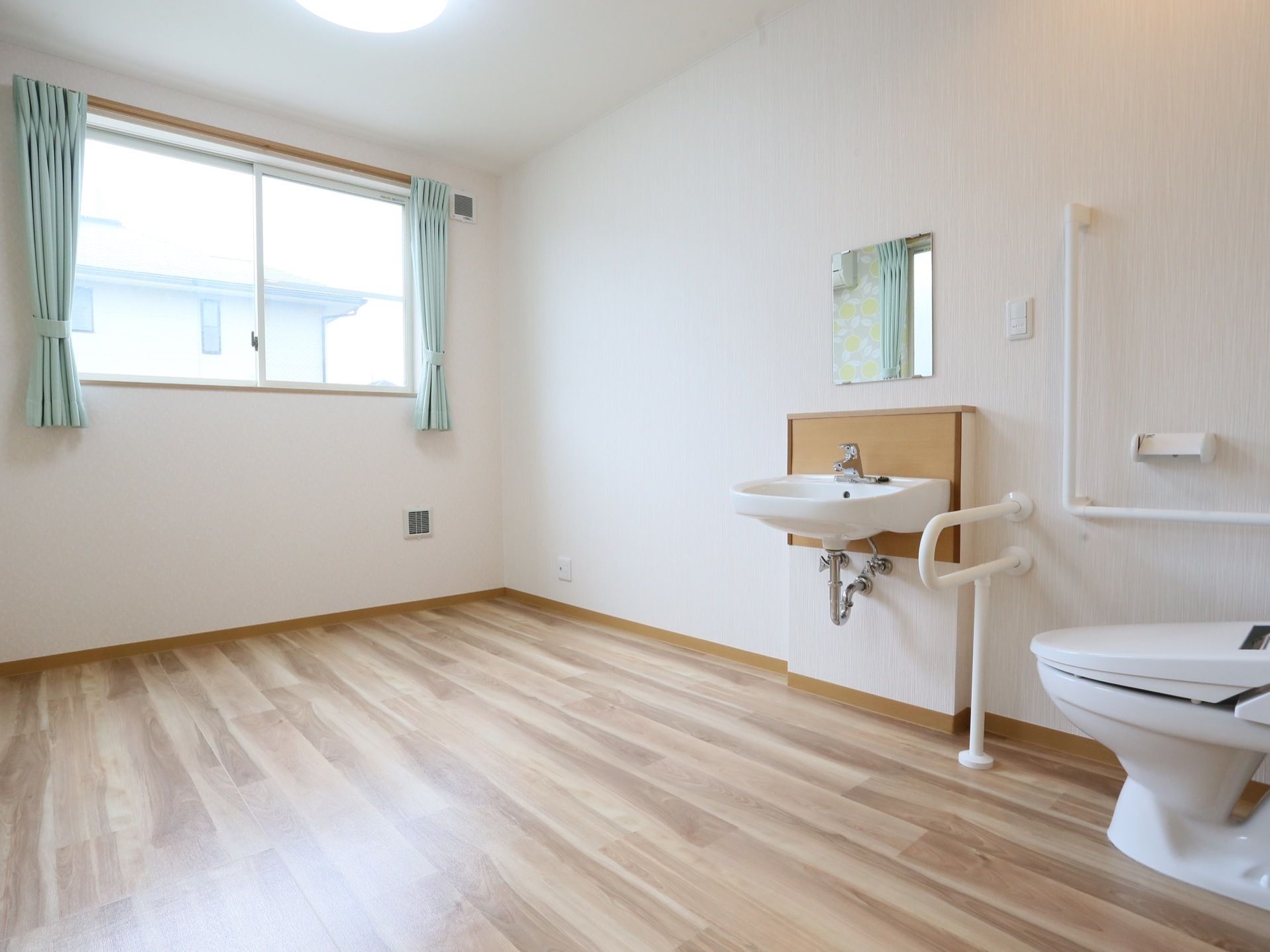 窓から明るい日が差し込む室内は、ゆったりとした広さを備える。トイレには手すりが設置され、アクセスも抜群である。