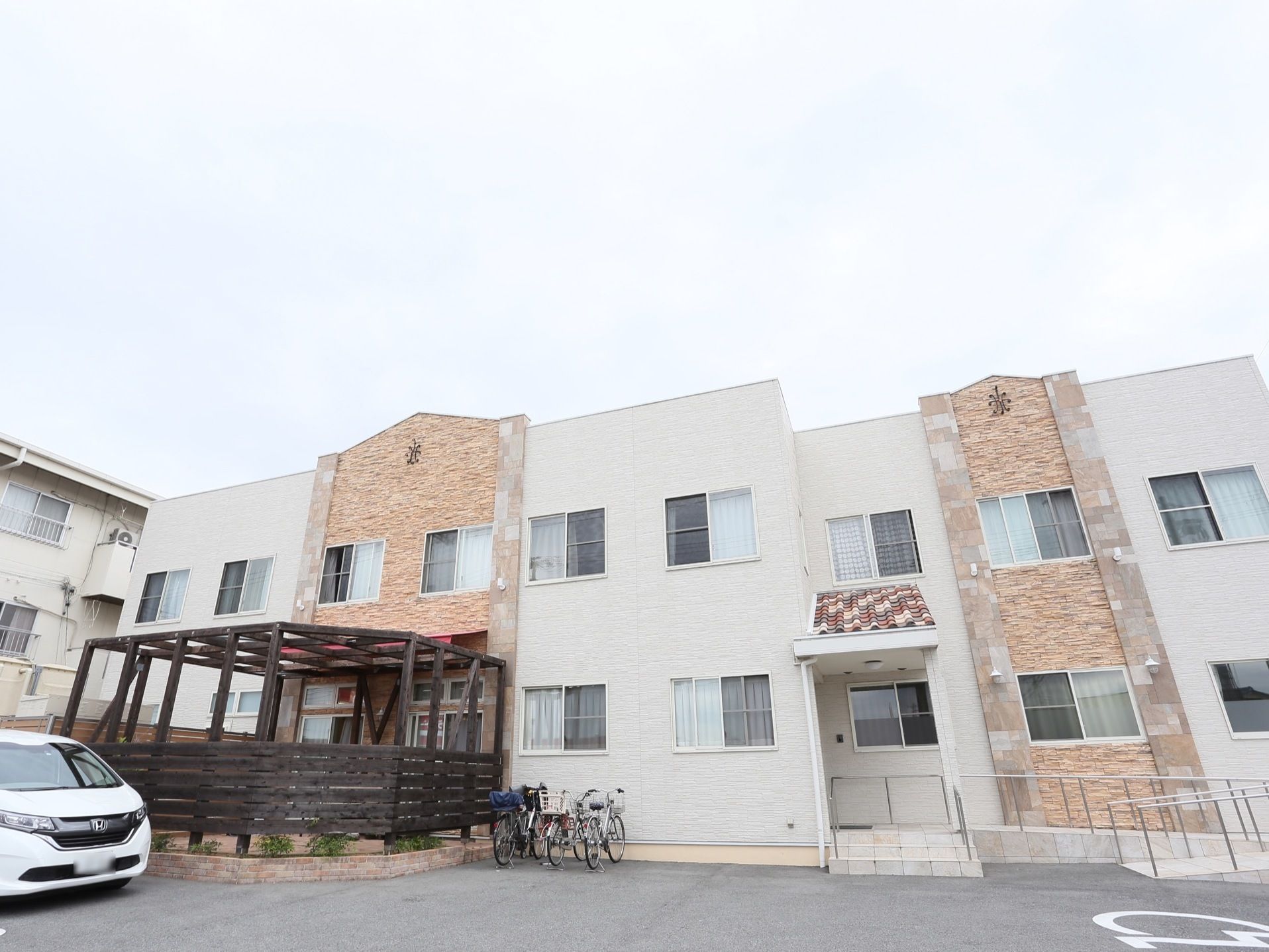 白と茶を基調としたモダンでシックな外観で、木製パーゴラを備えたテラスでは観賞用野菜などを育てている。