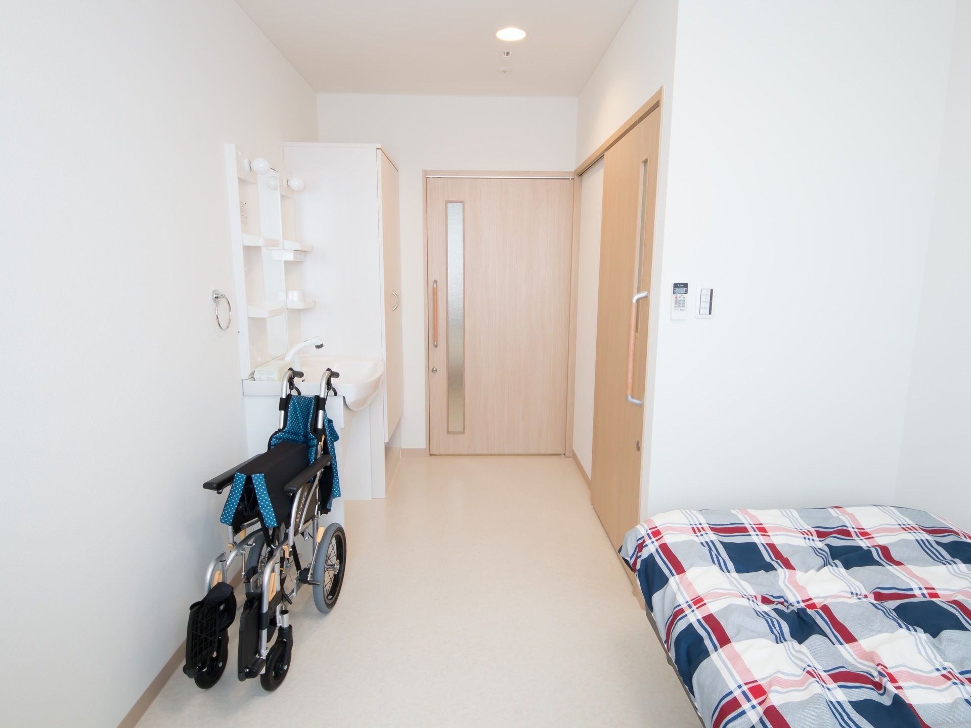 個室の部屋にベッドが置かれている。そばには車椅子が置かれている。扉は引き戸になっており、スムーズに出入りしていただける。