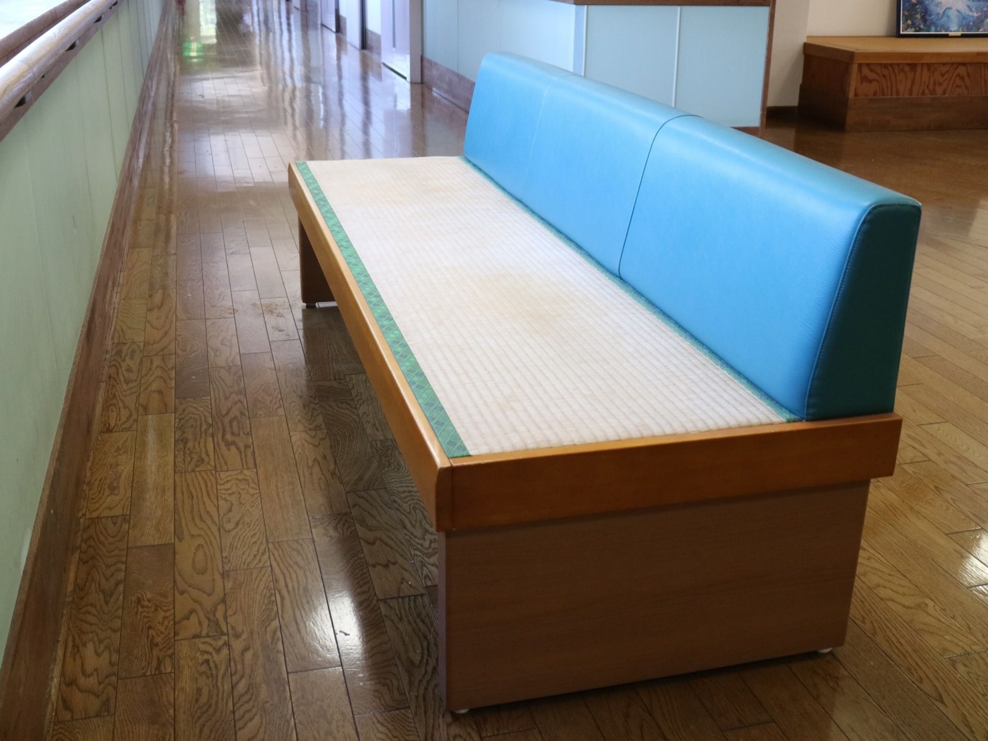 座面が畳で作られた、背もたれの青いベンチが窓側に向いて置かれている。壁は緑色で塗装され、手すりがある。