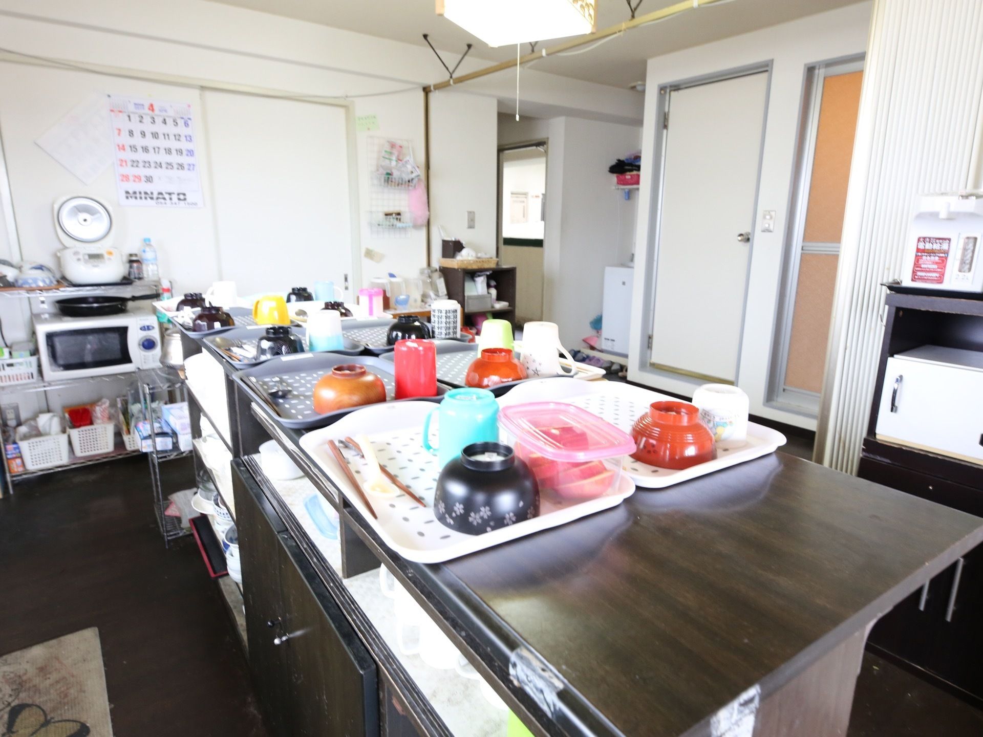 キッチンのカウンターの上に、複数のトレイが並べられており、それぞれにお椀や橋、コップが載せられている。
