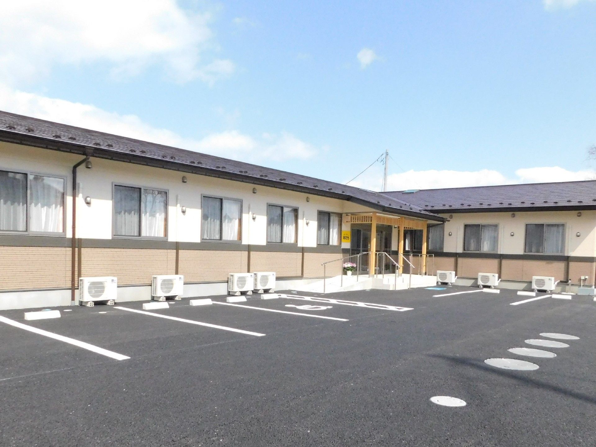 駐車場と建物が写っている写真。青空が広がっていて天気が良いのが分かる