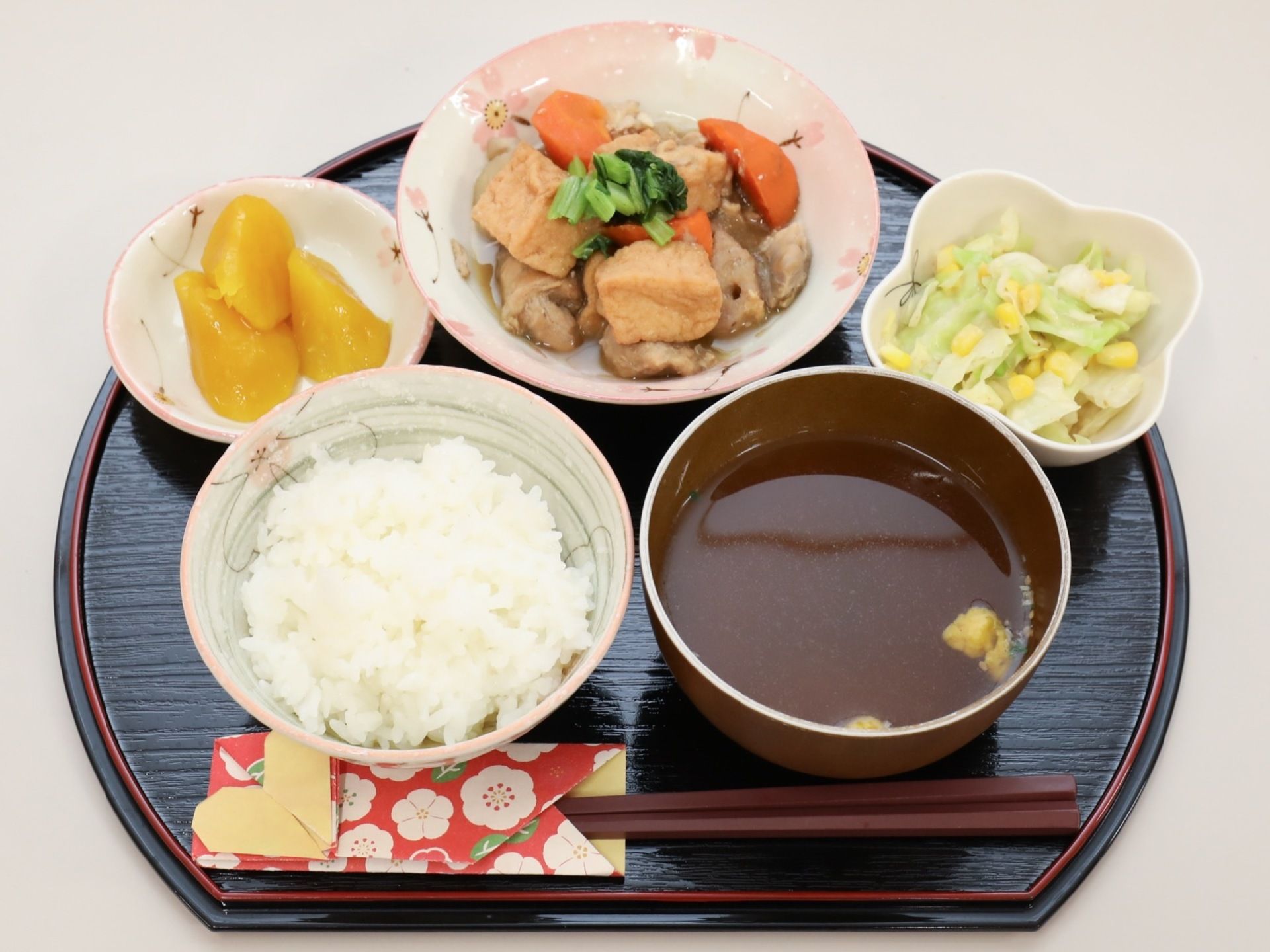 和食メニューがトレーに乗っている。白米、汁物、漬物、肉に果物といったバランスの良い食事が提供されている。