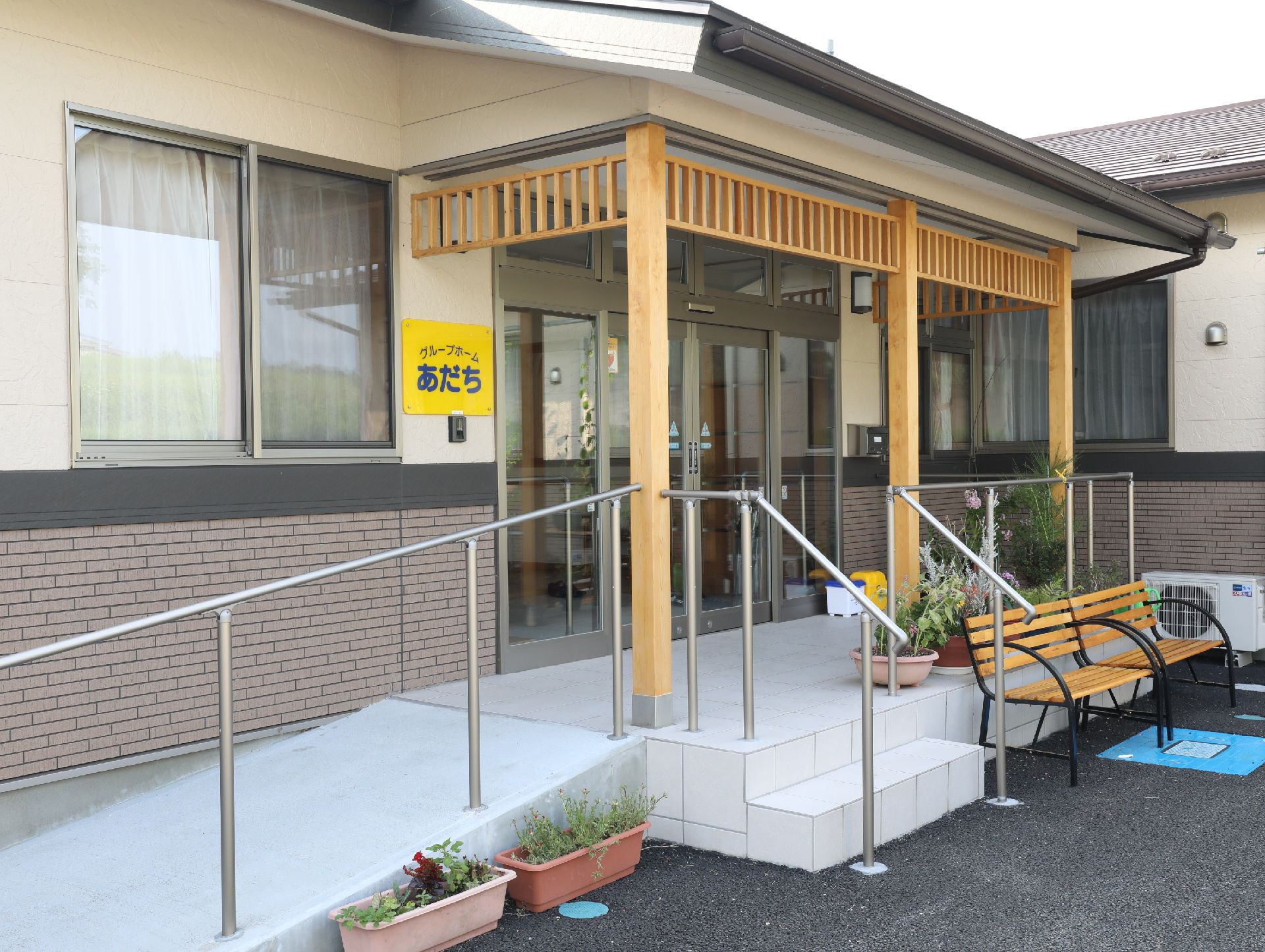 植木があり、ベンチとスロープのある自動ドア付きエントランス