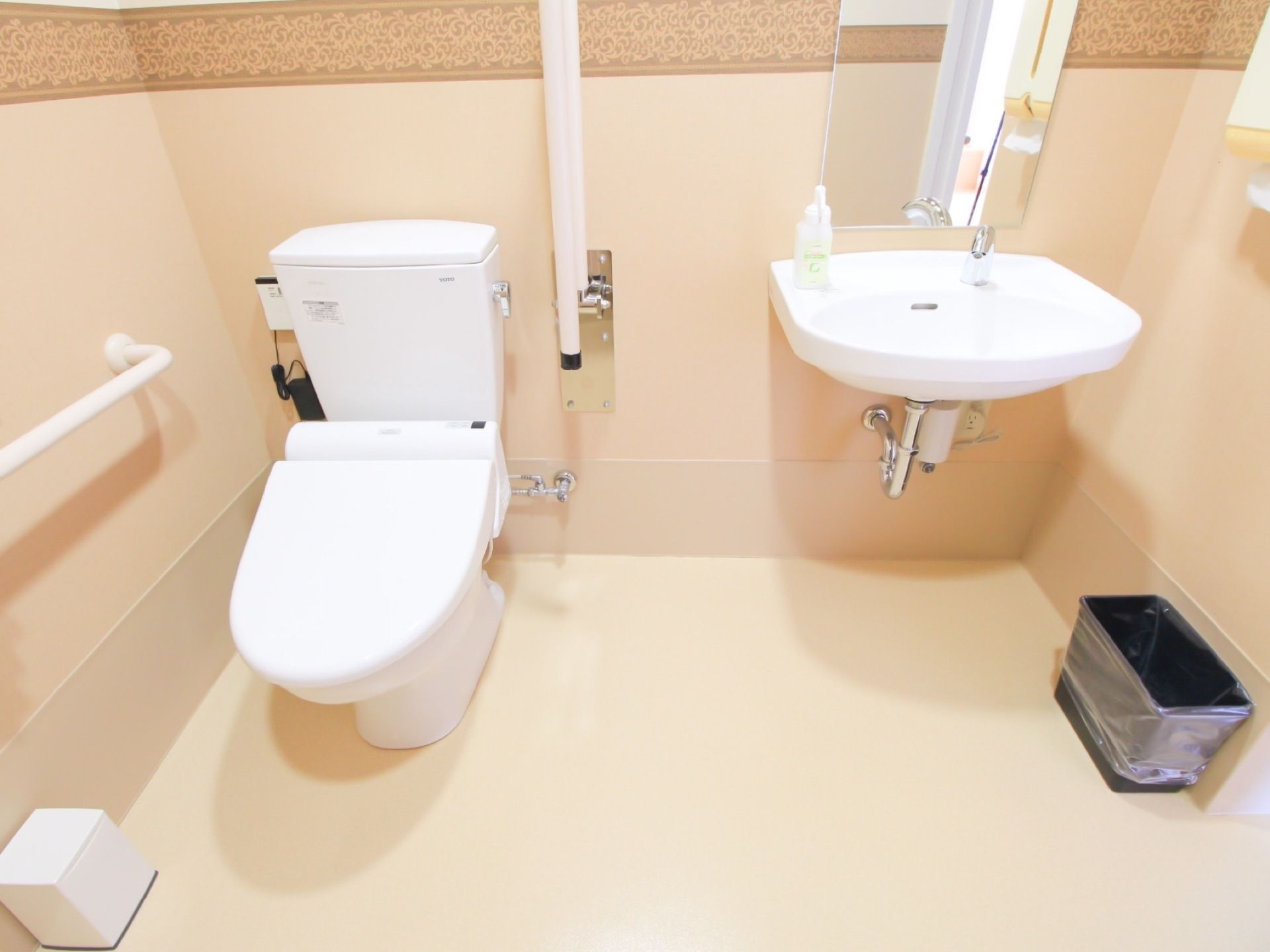 洗面台が備え付けられている広々としたトイレで、ハンドソープが用意されている。床には、ごみ箱が置かれている。