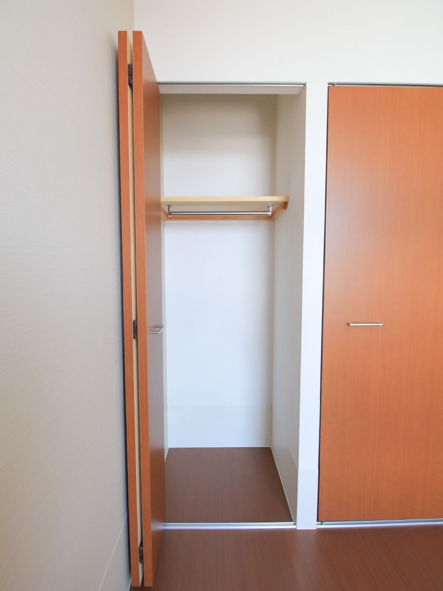 居室にクローゼットが備え付けられており、上部には棚が設けられている。ハンガーが掛けられるよう、ポールが取り付けられている。