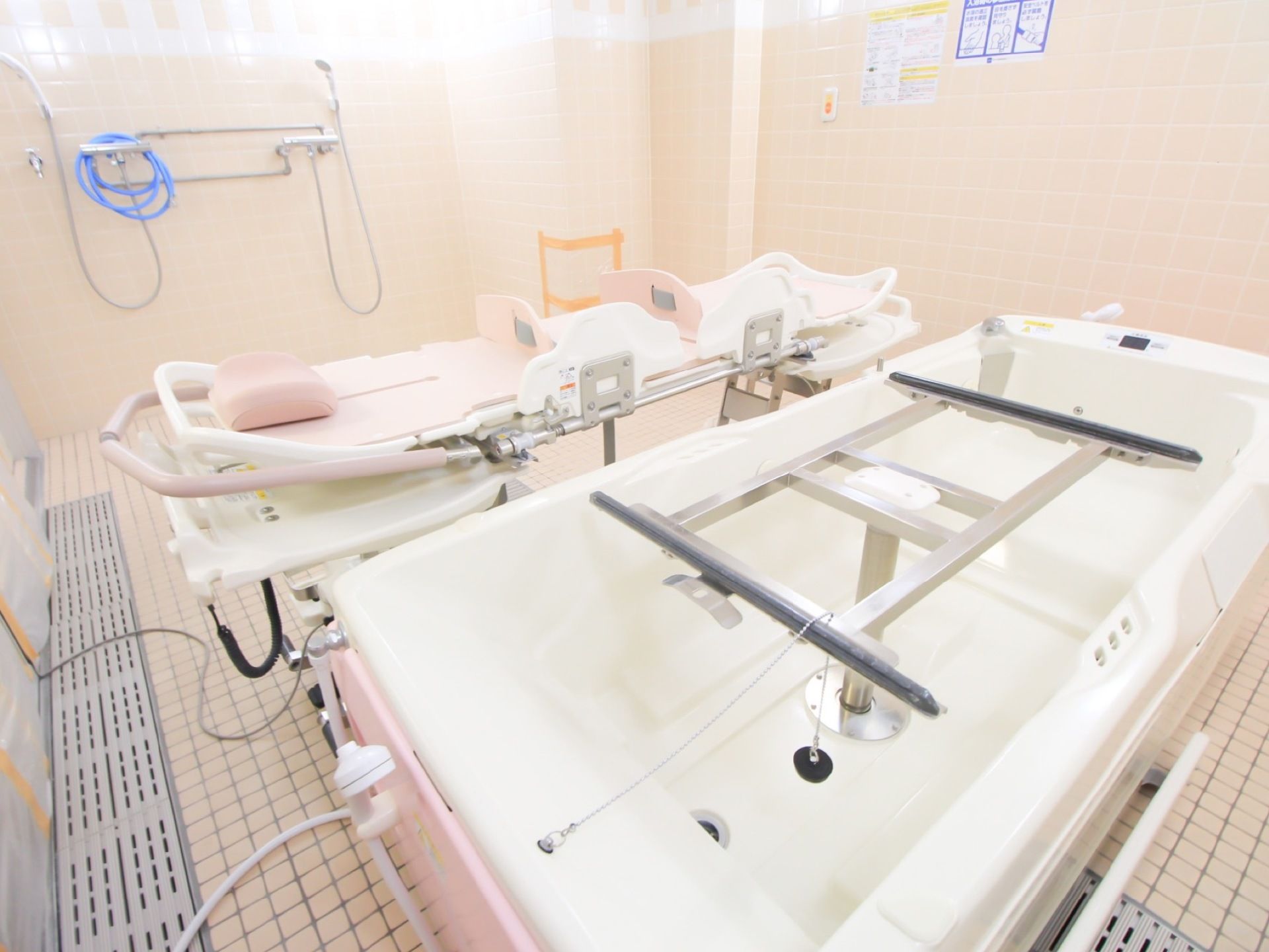 寝たままの姿勢でお湯に浸かっていただける、ストレッチャーの付いた浴槽が設置されている。壁に緊急通報装置がある。
