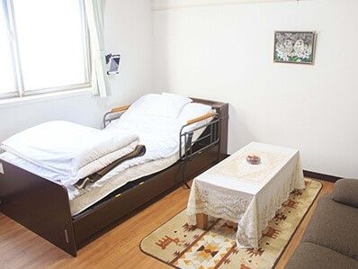 介護用ベッドと机が写っている一室の様子。窓から明るい日差しが差し込んでいる