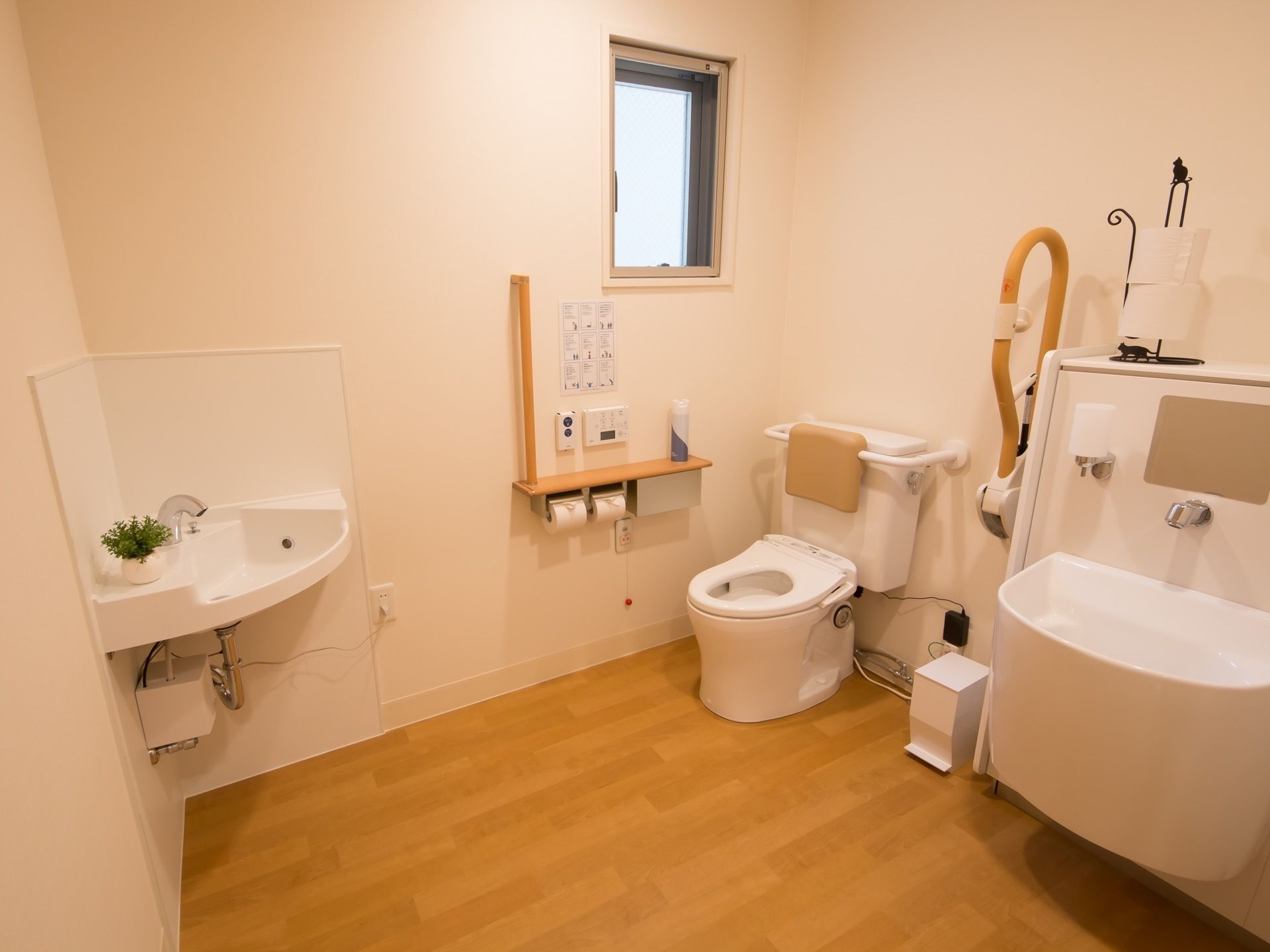 スペースを広く設けたトイレ内に、便座の低い便器が備えつけられている。便器の隣には洗面台があり、蛇口やシンクも低めに設計されている。