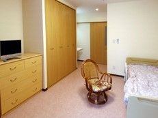 テレビ、いす、ベッドや収納が写っている部屋の様子
