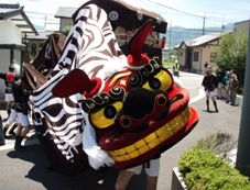 獅子舞がこちらを向いている写真。家庭を訪問している様子