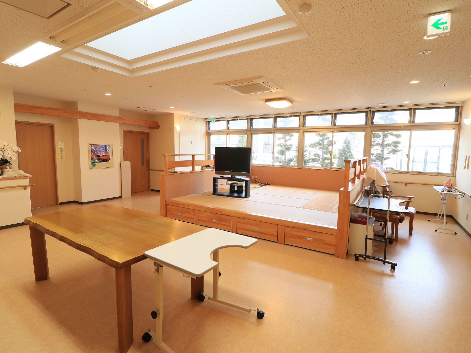 集会室は明るく広々とした空間になっている。テレビが設置された和室スペースが設けられている。テーブルやアイロン台が置かれている。