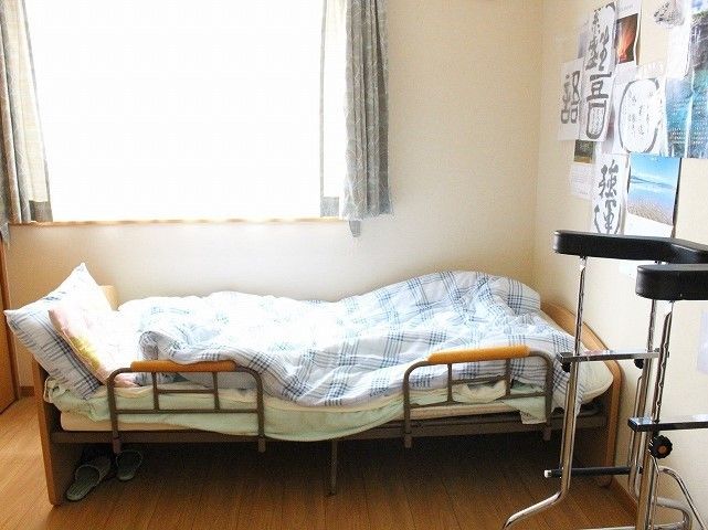 居室は窓が大きく大変明るい。ベッドの上には布団や枕が置かれ、柵も取り付けられている。