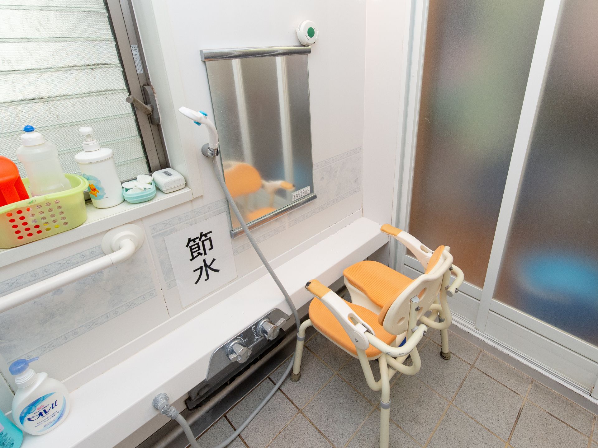 浴室の洗い場にはオレンジ色の椅子が設置されている。ひじ掛けがあり、立ち座りの際に体を支えられるので安全である。