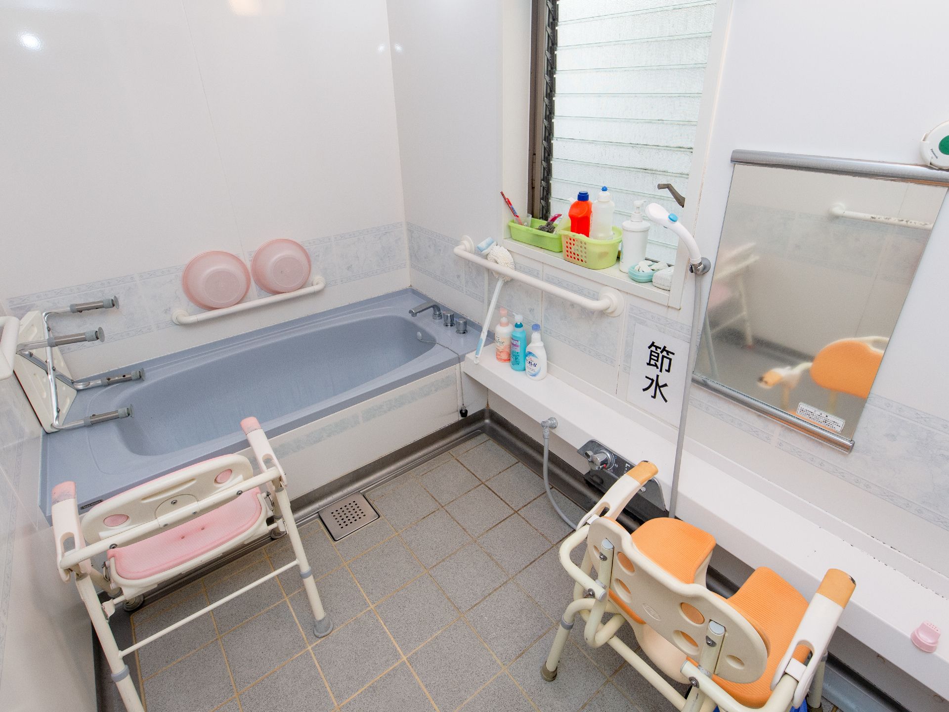 浴室には薄い紫色の浴槽が設置されている。安全面に配慮して、つかまっていただける手すりが設けられている。