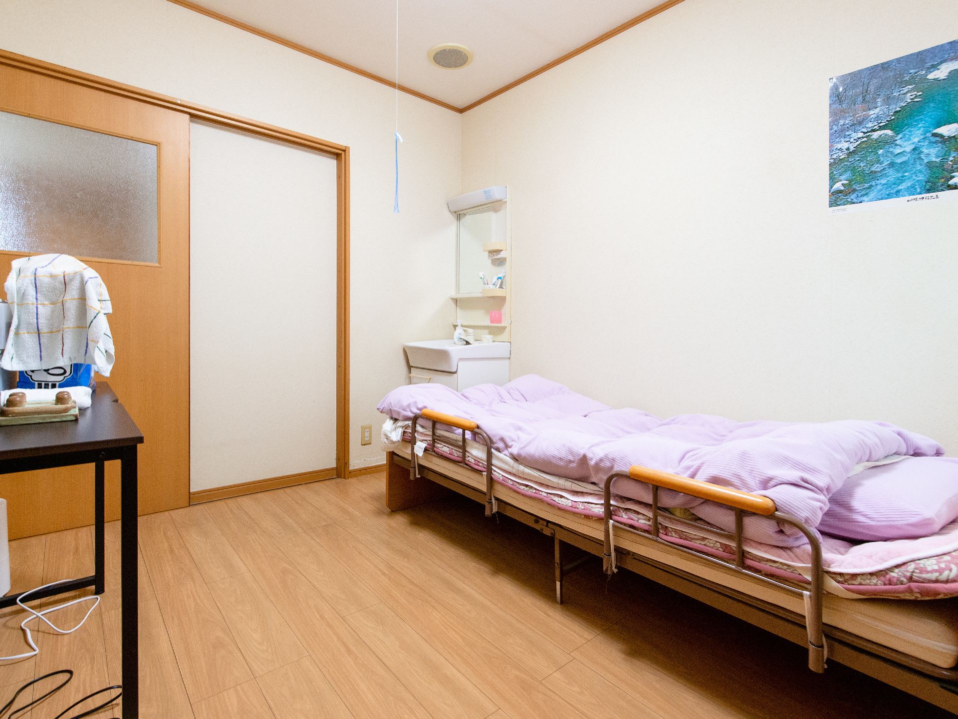 居室にはベッドと洗面台を設置している。白い壁にフローリングの床になっており、落ち着いた雰囲気である。
