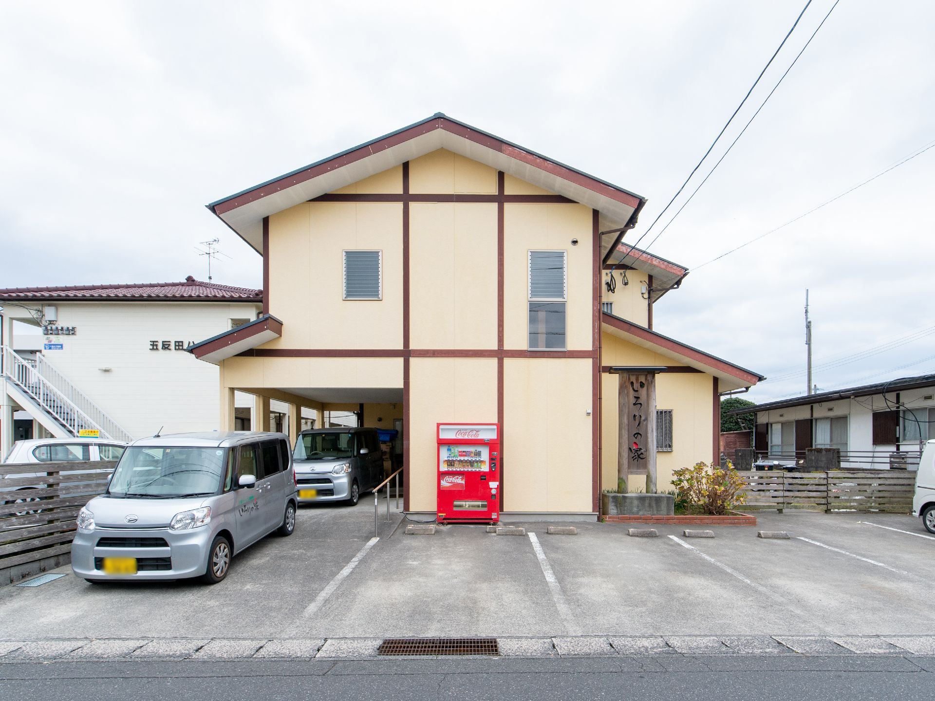 黄色と赤色の組み合わせが特徴的な外観の施設である。玄関前には、奥行きのある掘り込み式駐車スペースがある。