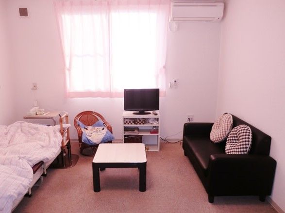 ベッド、机、ソファが写っている部屋。テレビが正面にある