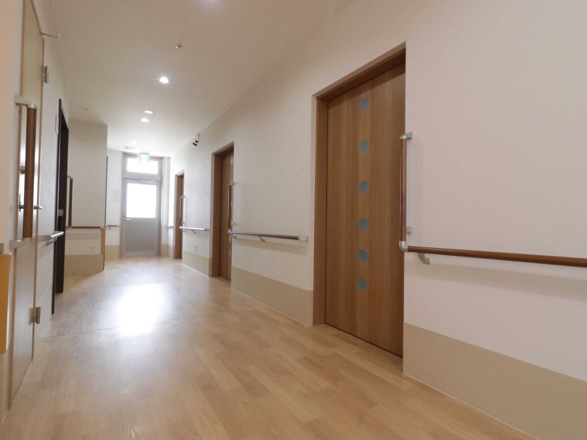 廊下の突き当たりに非常口の扉がついており、陽光が差し込むので明るい。木の温もりを感じられる内装である。