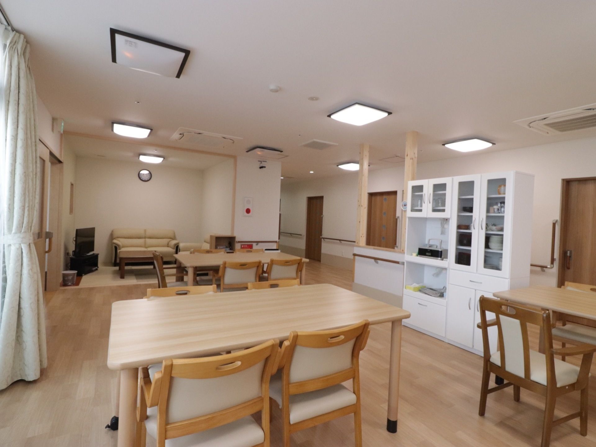 食堂兼リビングに集まっている入居者。電灯がついた明るい部屋は適度な飾りつけがされ家庭的な雰囲気。