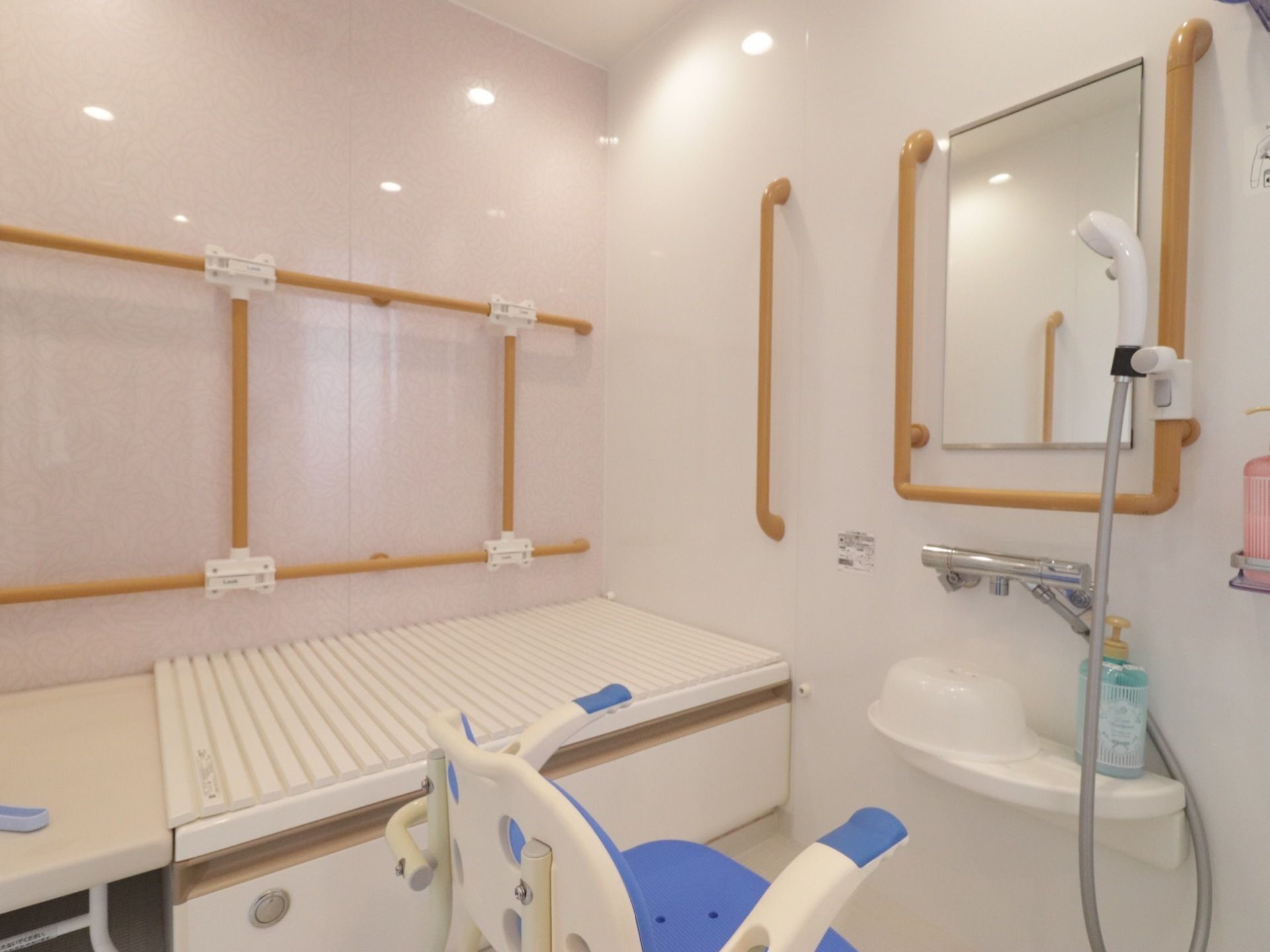 広い洗い場のある浴室。浴槽へは腰を掛けて安全に出入りができる。壁には手すりがたくさん設置されている。