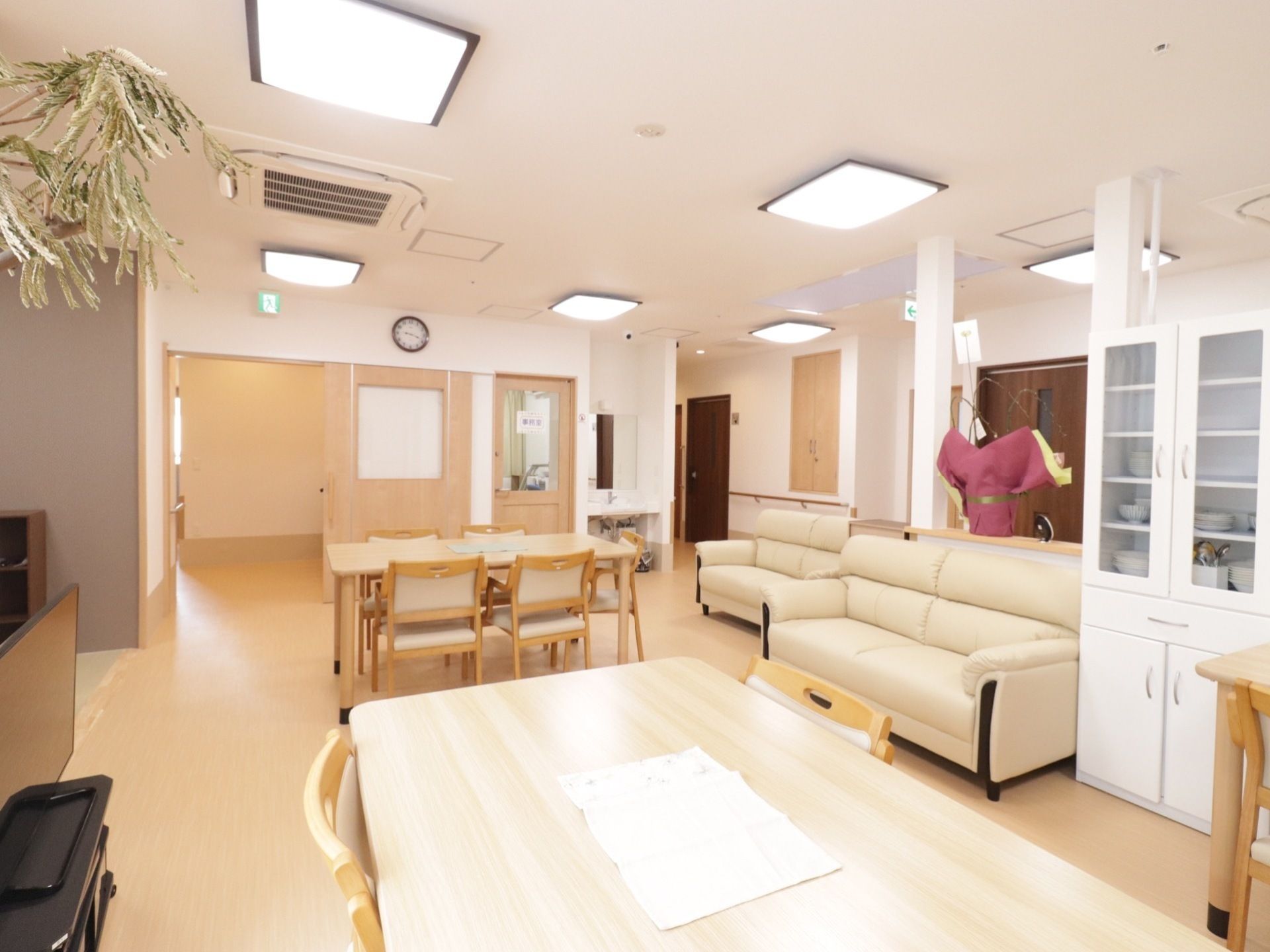 広く明るい食堂兼リビング。入居者はいすにゆったりと座り、思い思いの時間を過ごしている。